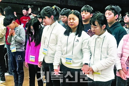 겨울성경학교 모임에서 초등부 주일학생들이 손을 마주잡고 함께 기도하고 있다.