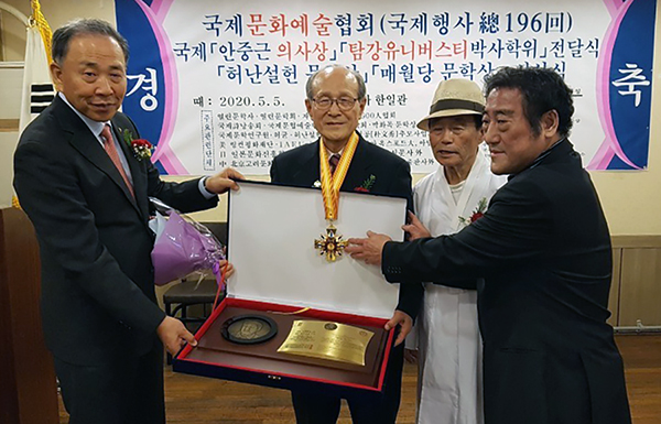 안중근 의사상을 수상한 전재규 장로가 안중근 의사와 자신의 사진이 새겨진 동패와 메달을 받고 기뻐하고 있다.
