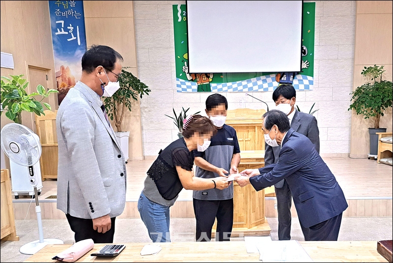 예천 송전교회 김병우 목사(사진 오른쪽)가 탈북자 교우 가정에 지원금을 전달하고 있다.(탈북인 가족의 얼굴은 본인 요청에 의해 모자이크 처리했습니다)