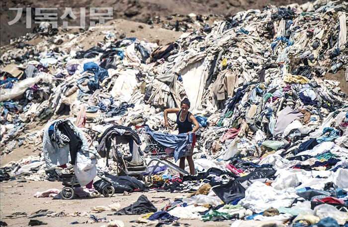 남미 칠레의 사막 위에 쌓인 옷 쓰레기산에서 사람들이 쓸만한 옷들을 찾고 있다.