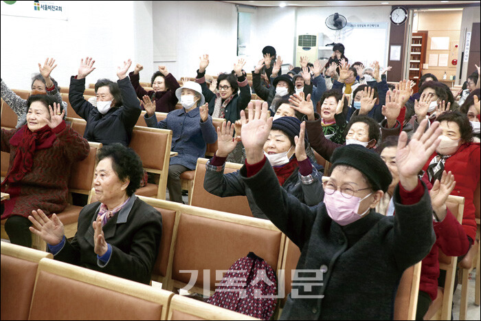 비전실버대학 개강식에서 동네 어르신들이 신현수 목사의 메시지에 따라 두 손을 높이 들고 인사하고 있다.