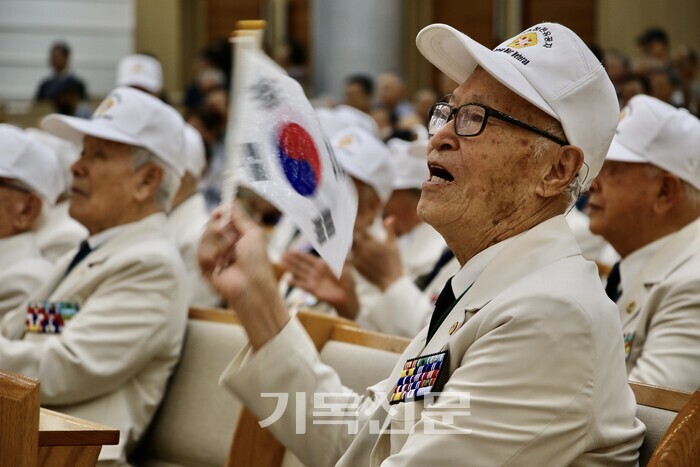 한국전쟁참전유공자 대전서구지회 참전용사들이 새로남기독초등학교 학생들의 공연에 맞춰 태극기를 흔들고 있다.