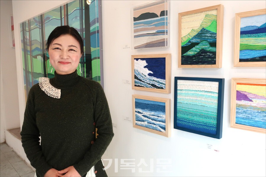 제주에서 태어나고 자라 자신의 작품에 제주의 아름다운 풍경을 담아온 강진주 작가가 ‘더 플레이스 오브 토브’라는 주제로 19번째 개인전을 열었다. 이번 개인전에서 강진주 작가는 직접 염색하고 직조한 실들로 하나님의 창조세계를 그려내며, 단순히 자연의 아름다움을 넘어 하나님 안에서 선하고 완전해진다는 신앙 고백을 담았다.